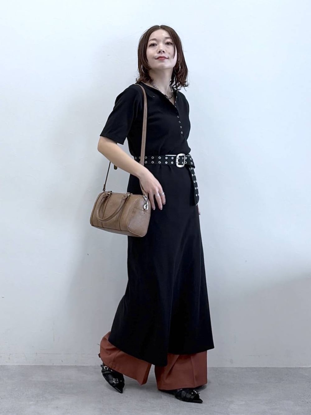 ブラウン系のボストンバッグ、ブラウン系のスラックス、ブラック系のベルトを着用したレディースの春コーディネートの8枚目の写真