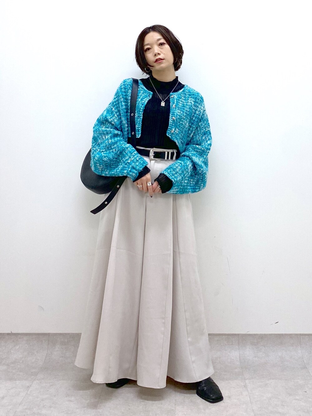 ベージュ系のスラックス、ブラック系のトップス、ブルー系のカーディガン/ボレロを着用したレディースの冬コーディネートの5枚目の写真