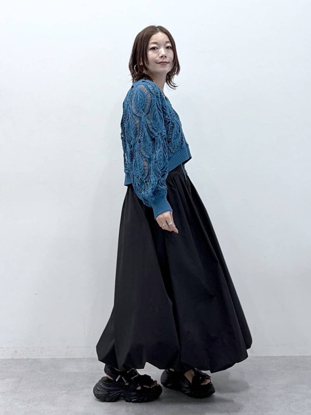 ブルー系のカーディガン/ボレロ、ブラック系のスカートを着用したレディースの春コーディネートの7枚目の写真