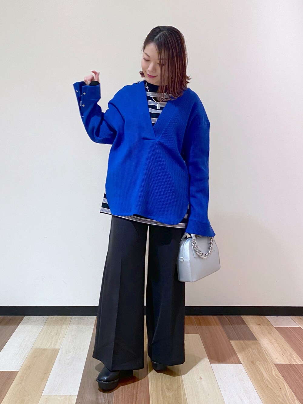 シルバー系のショルダーバッグ、ブラック系のブーツ、ブルー系のTシャツ/カットソーを着用したレディースの冬コーディネートの2枚目の写真