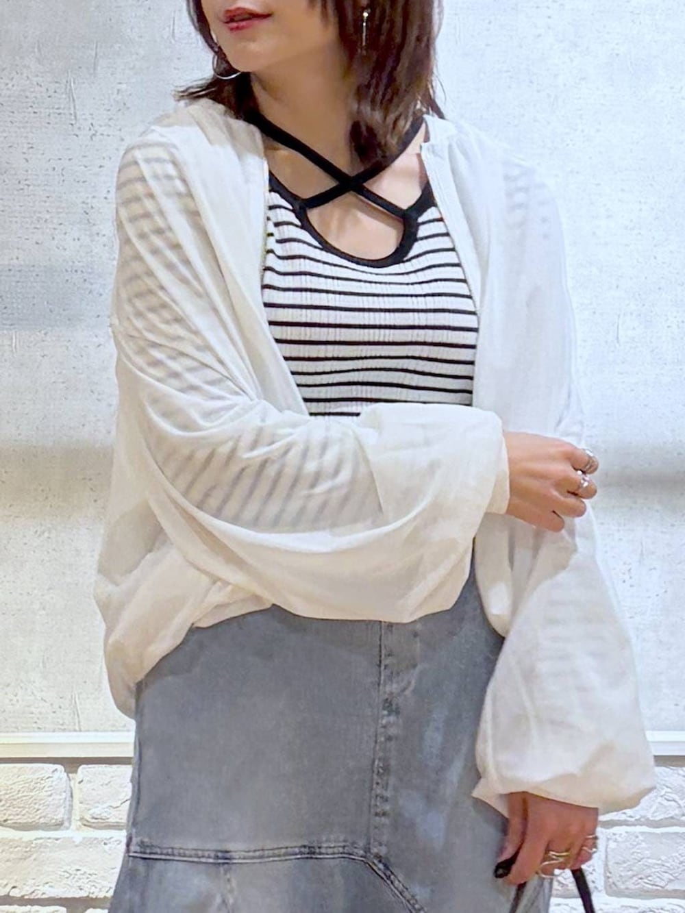 ブラウン系のハンドバッグ、ホワイト系のニット/セーター、ブラック系のサンダルを着用したレディースの春コーディネートの2枚目の写真