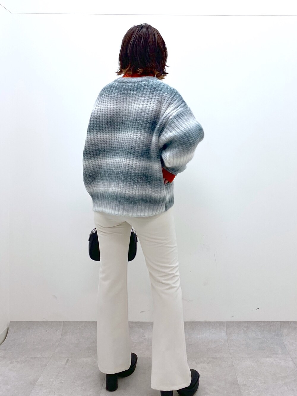 ブラック系のトップス、オレンジ系のトップス、ブラック系のバッグを着用したレディースの秋コーディネートの4枚目の写真