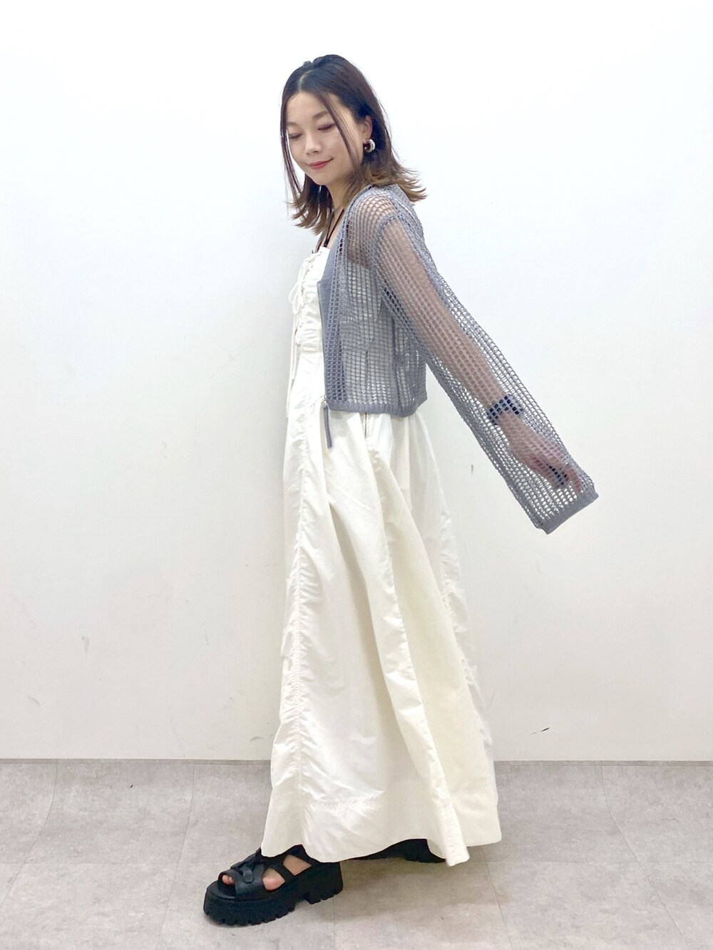 ホワイト系のワンピース、グレー系のカーディガン/ボレロ、ブラック系のサンダルを着用したレディースの春コーディネートの4枚目の写真