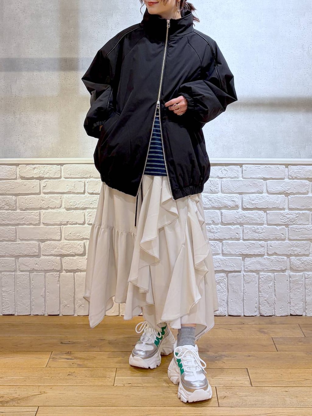 ホワイト系のスニーカー、ベージュ系のスカート、ブラック系のナイロンジャケットを着用したレディースの冬コーディネートの2枚目の写真