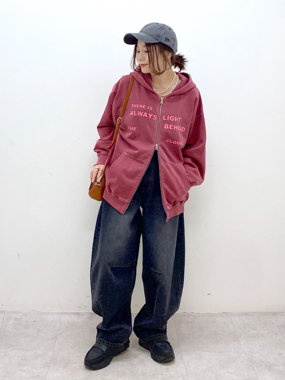 レッド系のスウェット、ブラック系のデニムパンツ、ブラック系のローファーを着用したレディースの冬コーディネートの4枚目の写真