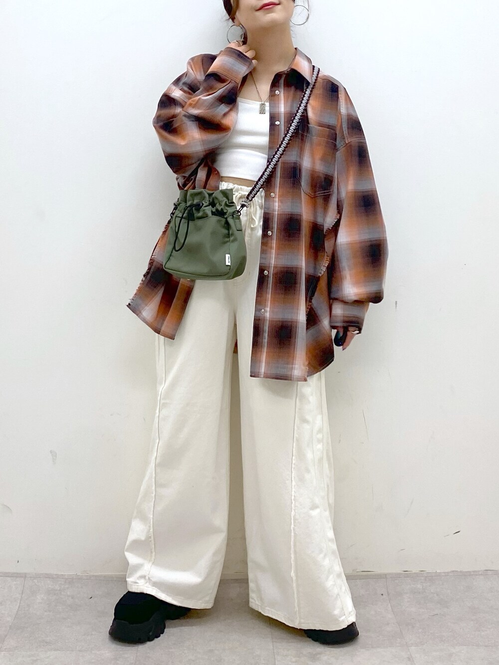 ホワイト系のデニムパンツ、ブラック系のスニーカー、グリーン系のショルダーバッグを着用したレディースの夏コーディネートの3枚目の写真