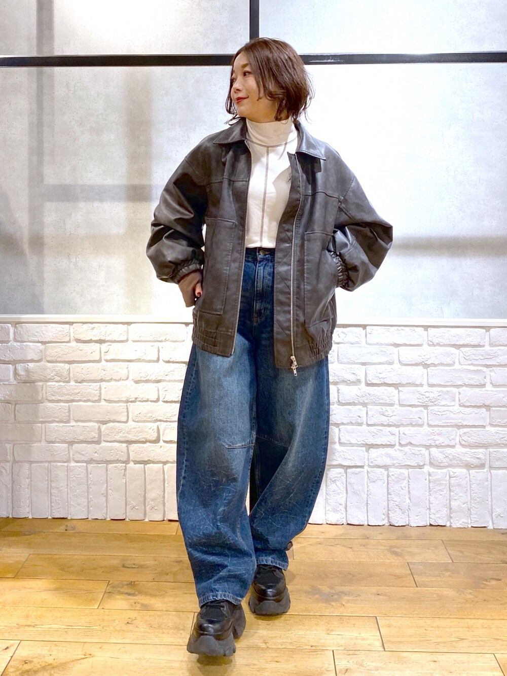 グレー系のブルゾン、ブルー系のデニムパンツ、ブラック系のブーツを着用したレディースの冬コーディネートの4枚目の写真