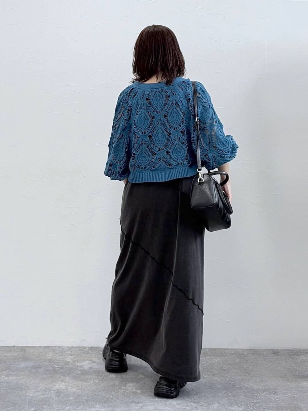 ブラック系のワンピース、ブルー系のカーディガン/ボレロ、ブラック系のボストンバッグを着用したレディースの春コーディネートの5枚目の写真