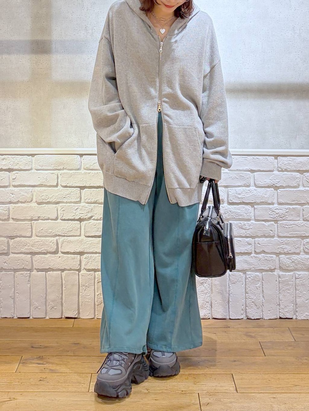 グレー系のスニーカー、グレー系のパーカー、ブラック系のショルダーバッグを着用したレディースの春コーディネートの3枚目の写真