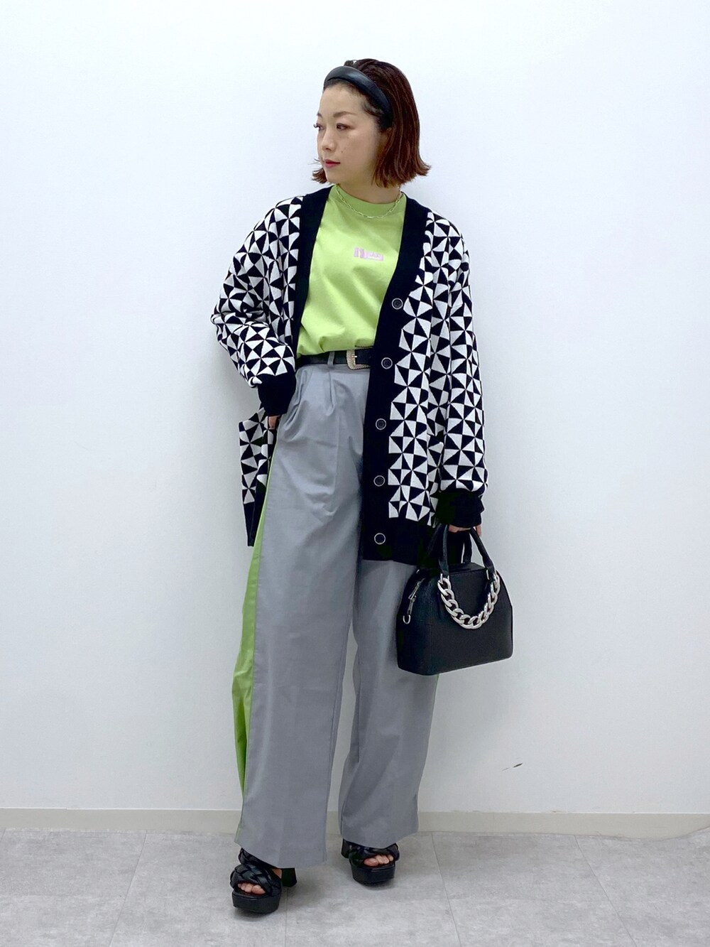 ホワイト系のカーディガン/ボレロ、グレー系のスラックス、ブラック系のショルダーバッグを着用したレディースの春コーディネートの2枚目の写真