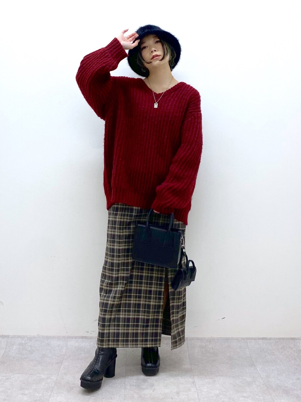 レッド系のニット/セーター、グリーン系のスカート、ブラック系のブーツを着用したレディースの冬コーディネートの5枚目の写真