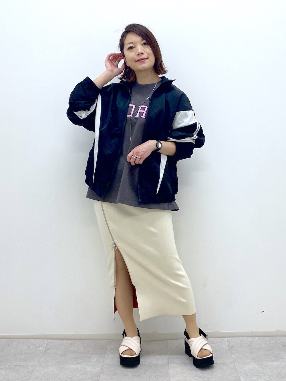 ブラック系のブルゾン、グレー系のTシャツ/カットソー、ホワイト系のスカートを着用したレディースの春コーディネートの2枚目の写真
