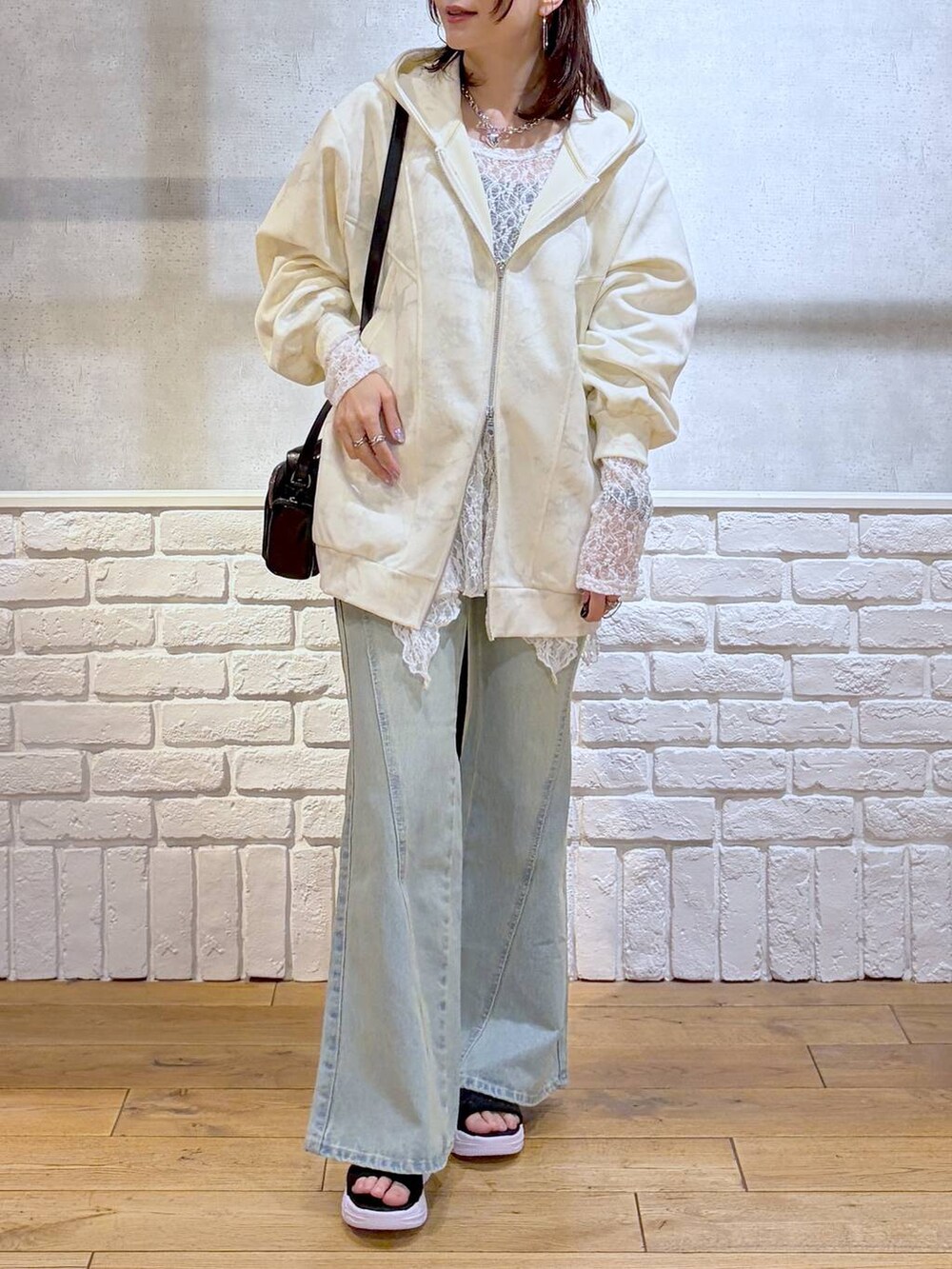ブルー系のデニムパンツ、ホワイト系のパーカー、ホワイト系のチュニックを着用したレディースの春コーディネートの3枚目の写真