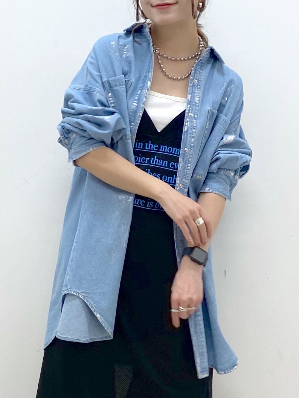 ブラック系のデニムパンツ、ホワイト系のスニーカー、ブラック系のワンピースを着用したレディースの春コーディネートの2枚目の写真