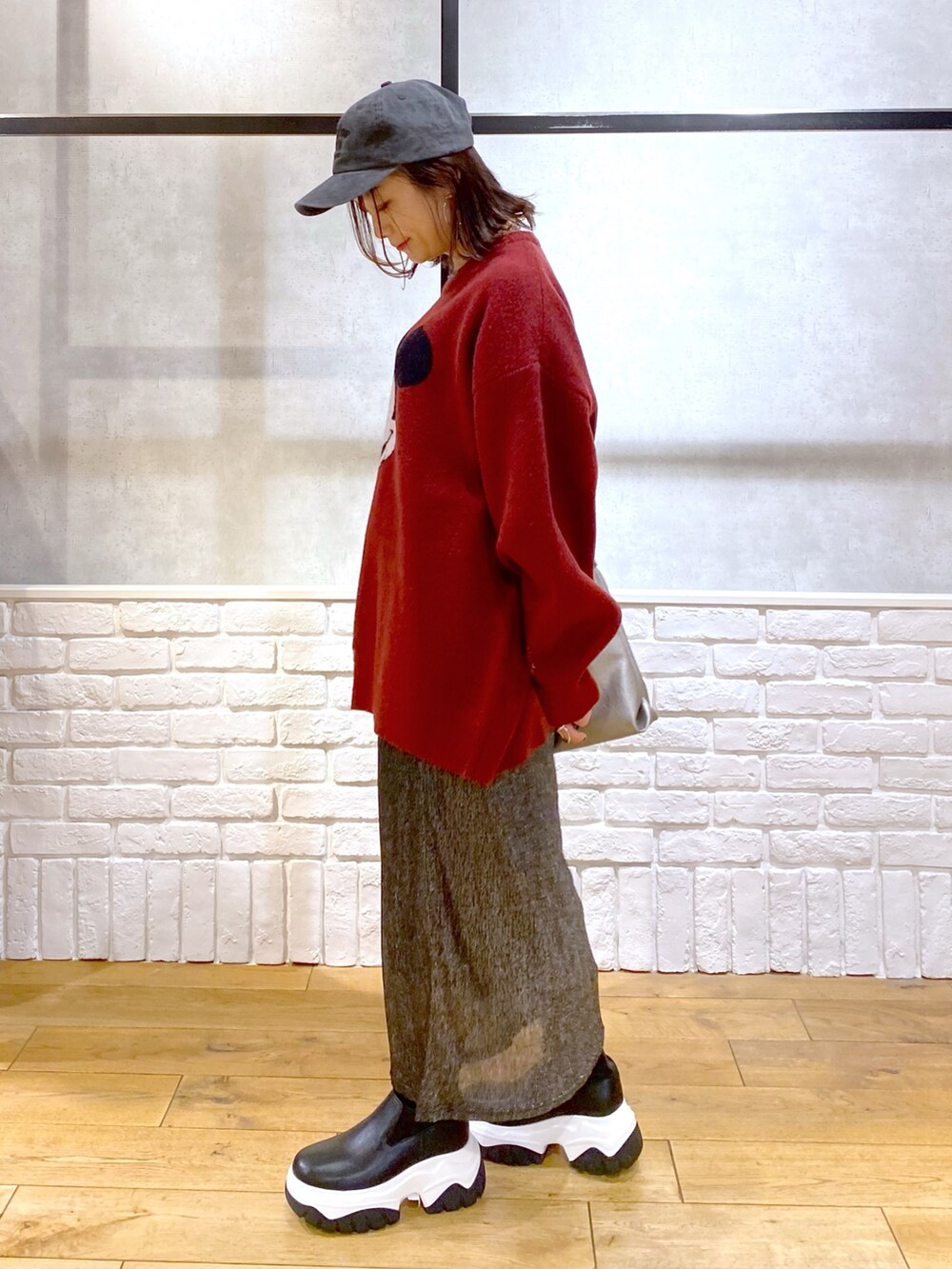 ブラック系のスカート、ブラック系のブーツ、シルバー系のトートバッグを着用したレディースの冬コーディネートの5枚目の写真