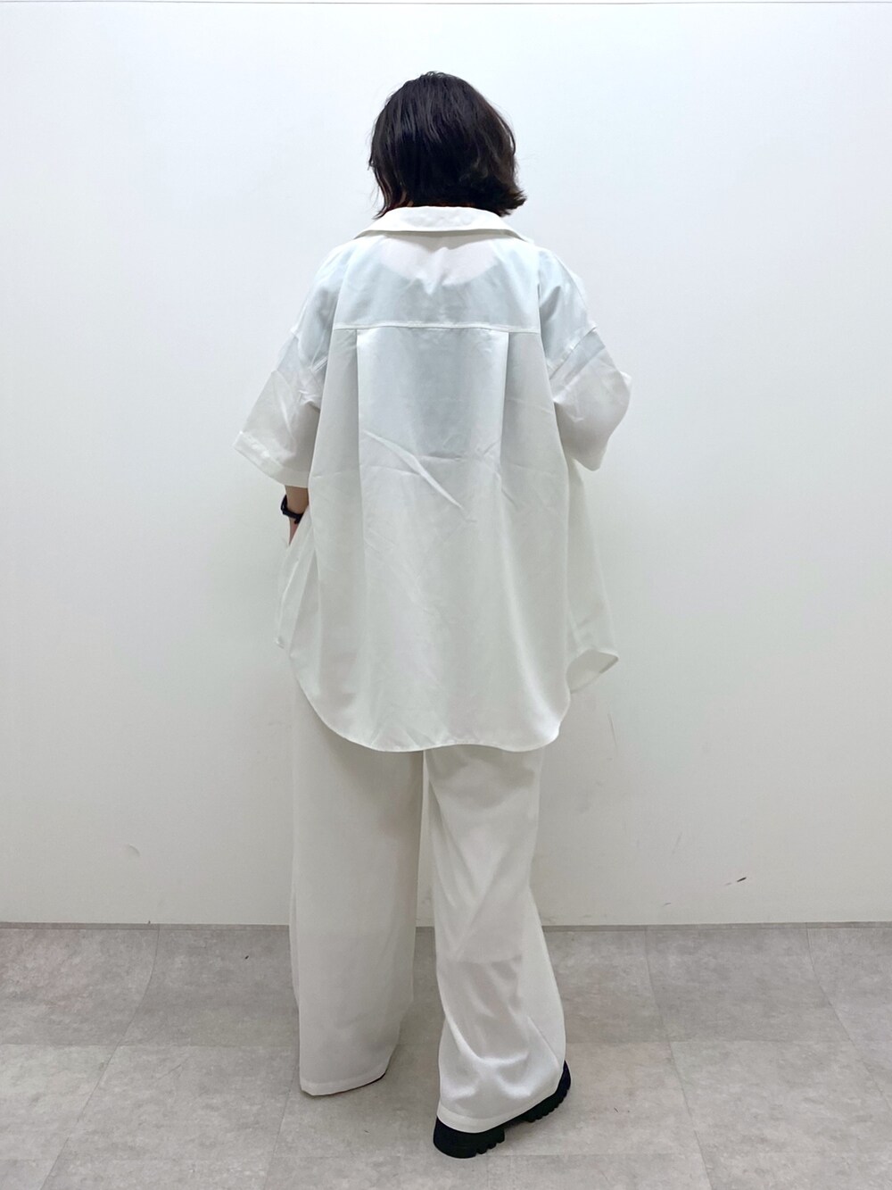 ホワイト系のパンツ、ブラック系のサンダル、ホワイト系のトップスを着用したレディースの春コーディネートの4枚目の写真