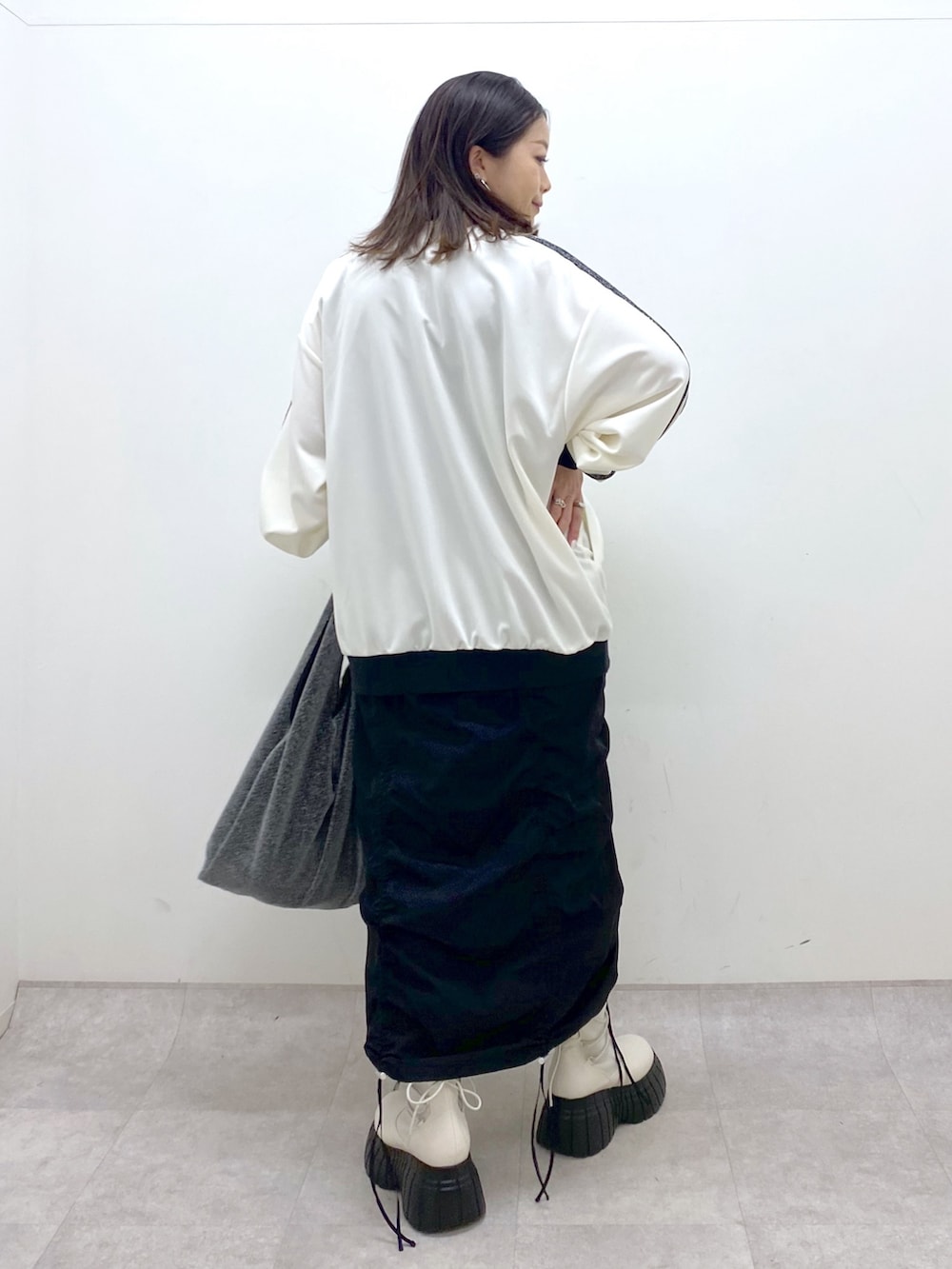 ブラック系のワンピース、ホワイト系のその他アウター、ブラック系のトートバッグを着用したレディースの冬コーディネートの3枚目の写真