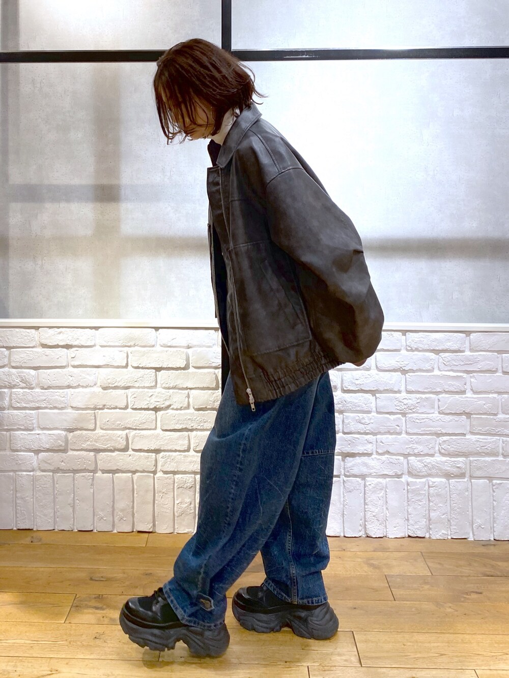 グレー系のブルゾン、ブルー系のデニムパンツ、ブラック系のブーツを着用したレディースの冬コーディネートの5枚目の写真