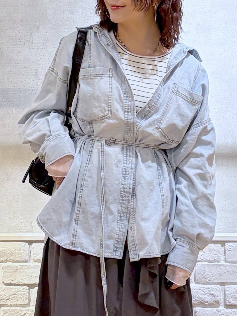 ブラック系のブーツ、ブラック系のショルダーバッグ、グレー系のスカートを着用したレディースの冬コーディネートの2枚目の写真