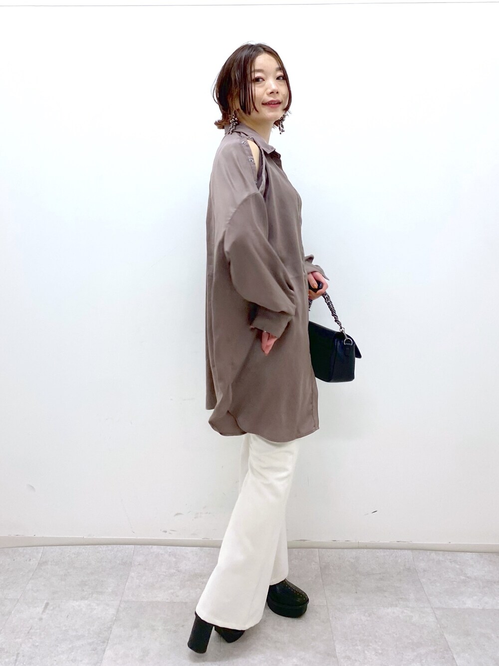 ホワイト系のパンツ、ブラック系のブーツ、ブラック系のバッグを着用したレディースの秋コーディネートの2枚目の写真