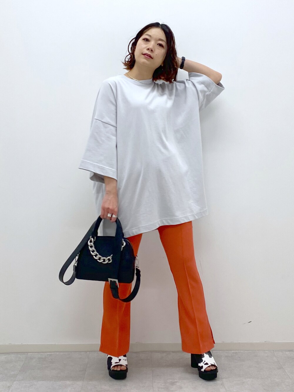 オレンジ系のその他パンツ、ホワイト系のサンダル、ブラック系のショルダーバッグを着用したレディースの春コーディネートの3枚目の写真