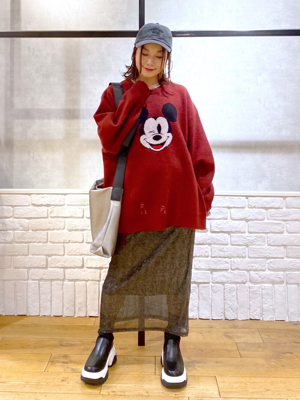 ブラック系のスカート、ブラック系のブーツ、シルバー系のトートバッグを着用したレディースの冬コーディネートの4枚目の写真