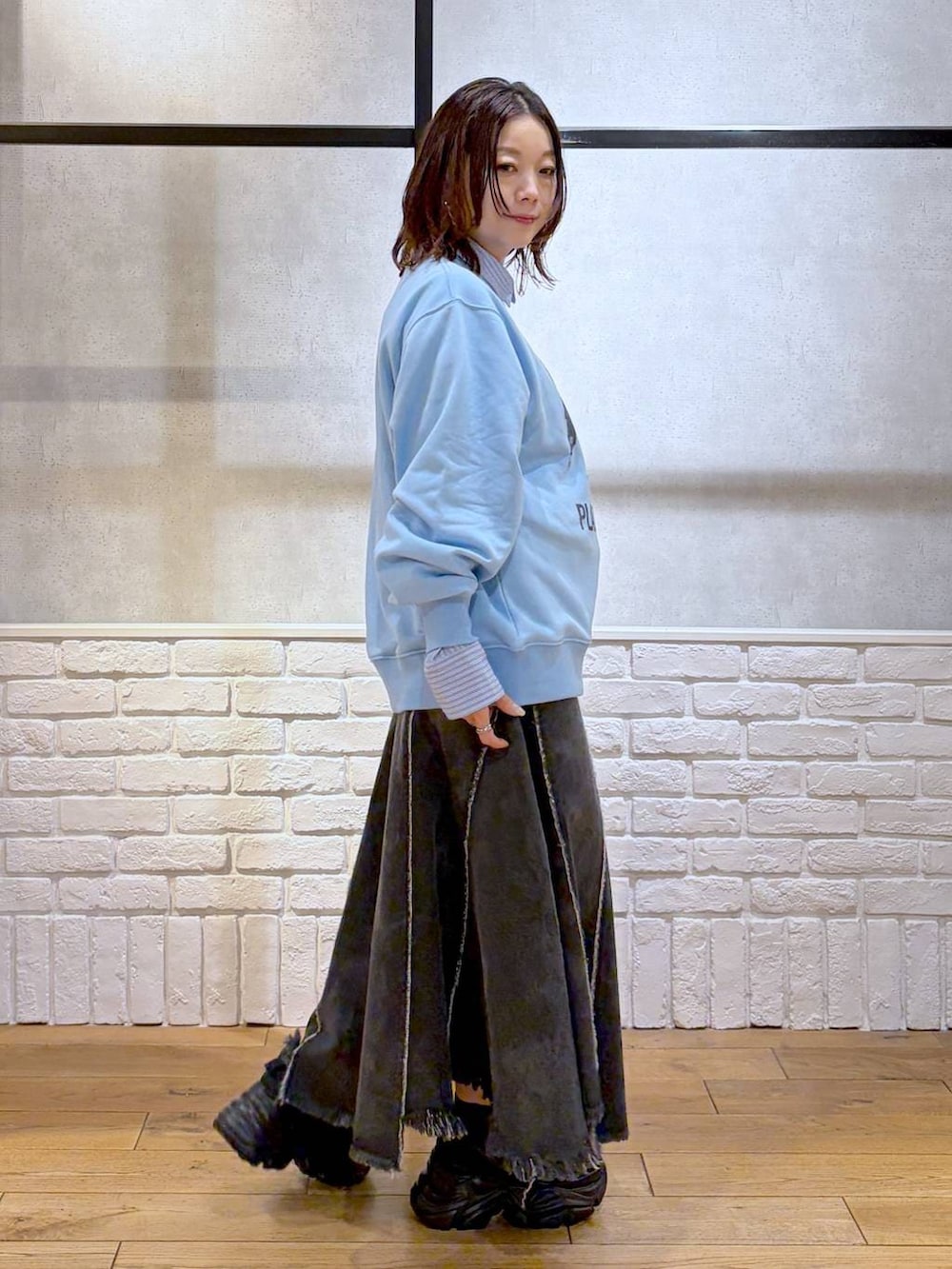 ブラック系のスニーカー、ブラック系のハンドバッグ、ブラック系のデニムスカートを着用したレディースの春コーディネートの7枚目の写真