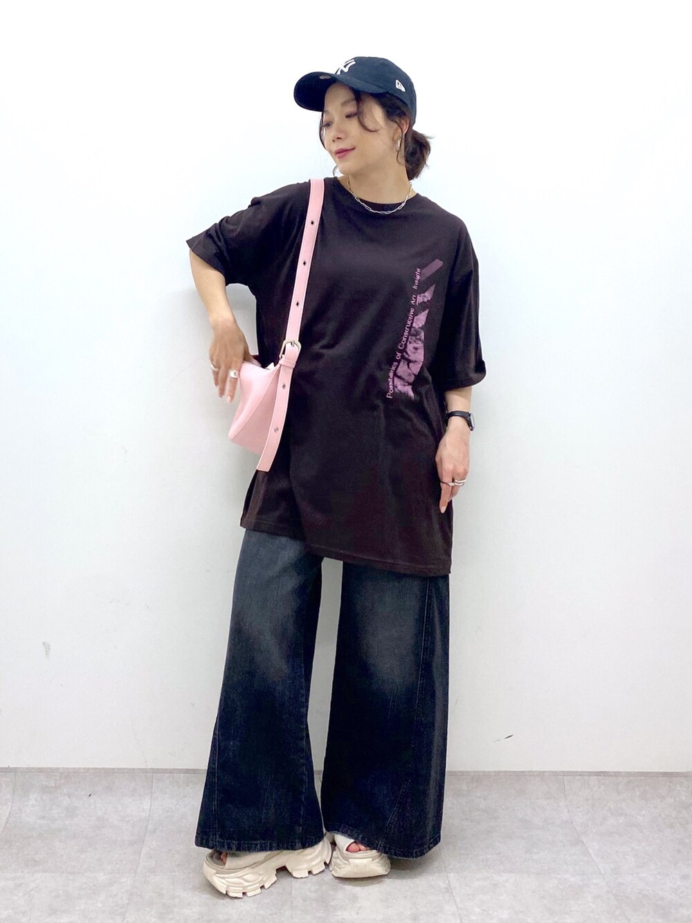 ピンク系のショルダーバッグ、ブラウン系のTシャツ/カットソー、ブラック系のデニムパンツを着用したレディースの夏コーディネートの2枚目の写真