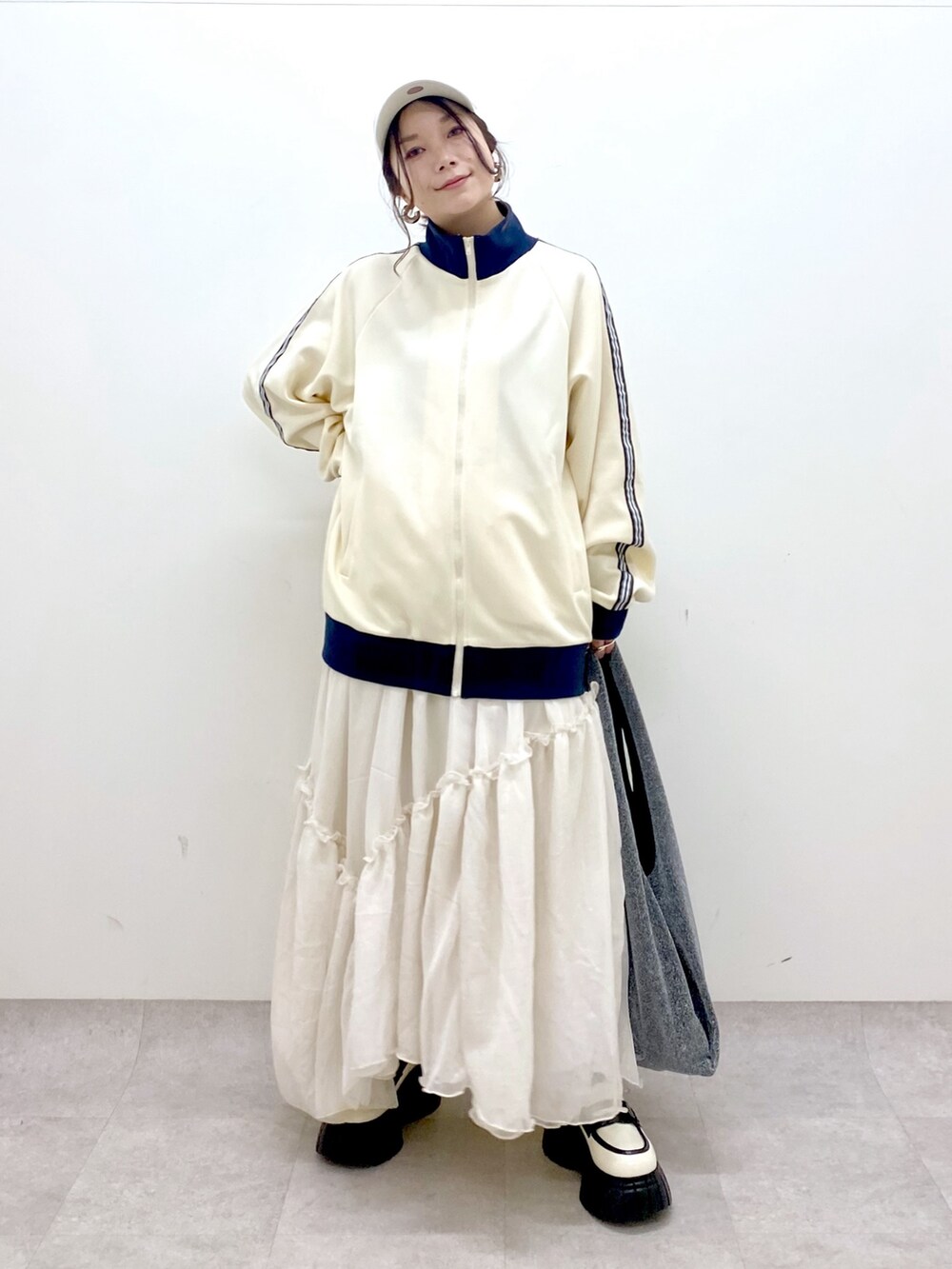 ホワイト系のセットアップ、ブラック系のトートバッグ、ホワイト系のスカートを着用したレディースの冬コーディネートの7枚目の写真