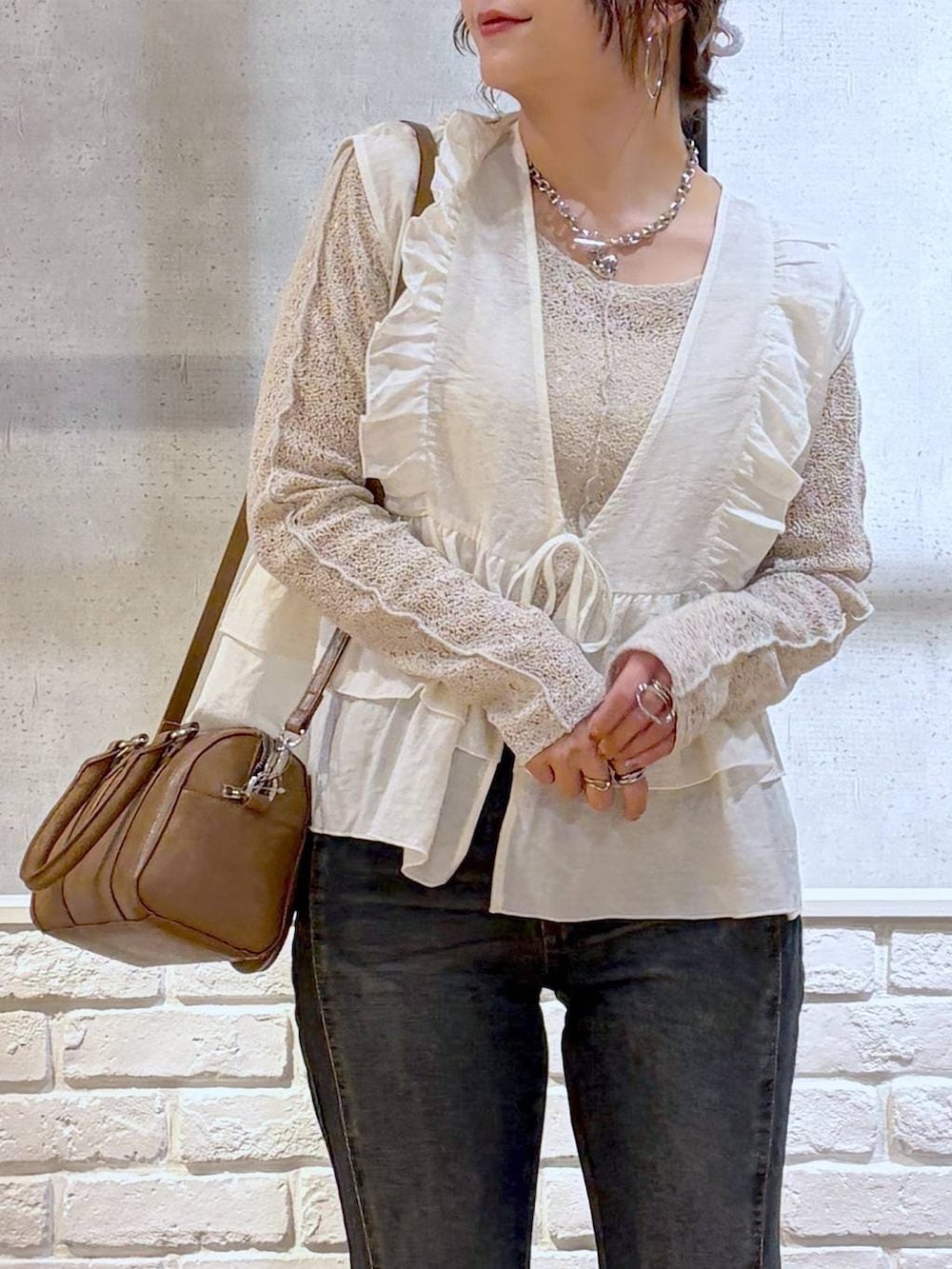 ブルー系のデニムパンツ、ブラウン系のボストンバッグ、ブラウン系のサンダルを着用したレディースの春コーディネートの2枚目の写真