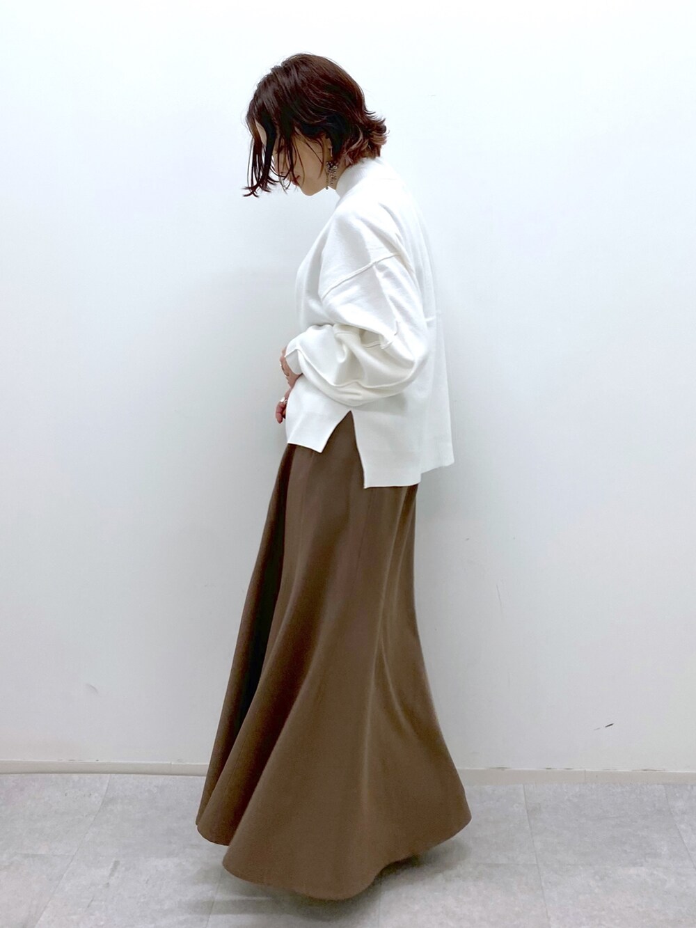 ホワイト系のブーツ、ブラウン系のスカート、ブラック系のバッグを着用したレディースの秋コーディネートの3枚目の写真