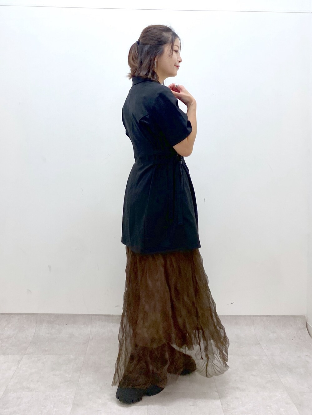 ブラック系のテーラードジャケット、ブラウン系のスカート、ブラック系のショルダーバッグを着用したレディースの夏コーディネートの7枚目の写真