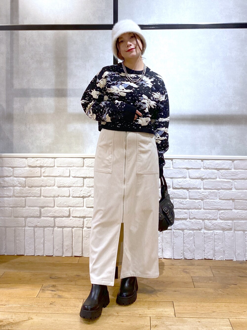 ブラック系のニット/セーター、ブラック系のハンドバッグ、ブラック系のブーツを着用したレディースの冬コーディネートの4枚目の写真