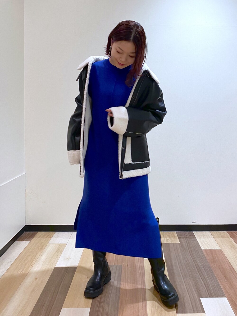 ブラック系のブルゾン、ブラック系のブーツ、ブルー系のワンピースを着用したレディースの冬コーディネートの5枚目の写真
