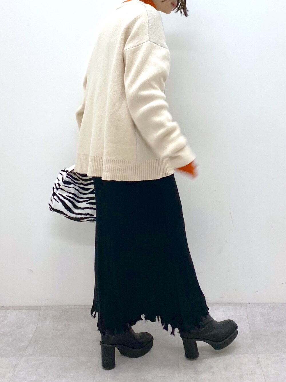 ホワイト系のトップス、オレンジ系のトップス、ブラック系のスカートを着用したレディースの冬コーディネートの4枚目の写真