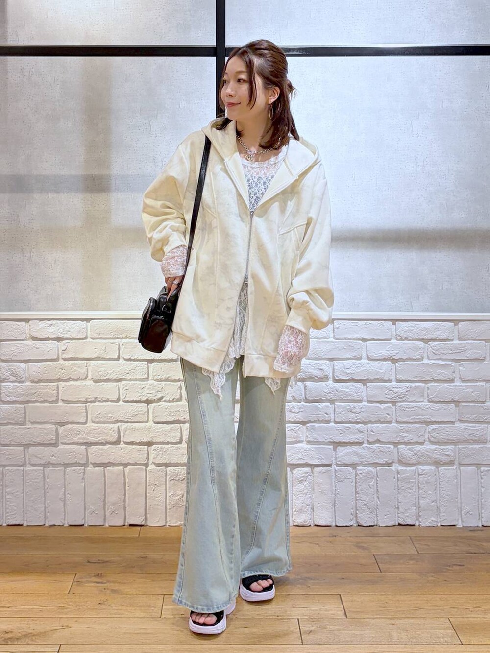 ブルー系のデニムパンツ、ホワイト系のパーカー、ホワイト系のチュニックを着用したレディースの春コーディネートの4枚目の写真