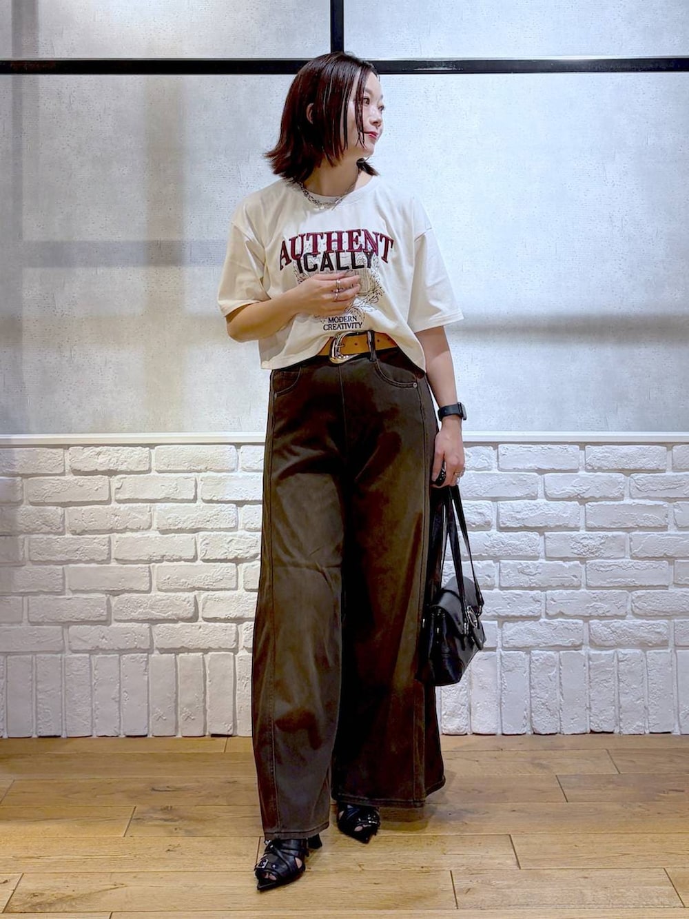 ブラウン系のデニムパンツ、ホワイト系のTシャツ/カットソー、ブラック系のサンダルを着用したレディースの夏コーディネートの5枚目の写真