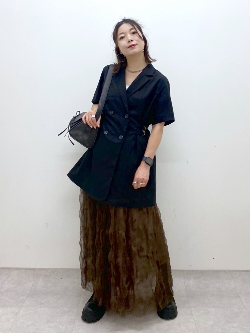 ブラック系のテーラードジャケット、ブラウン系のスカート、ブラック系のショルダーバッグを着用したレディースの夏コーディネートの4枚目の写真