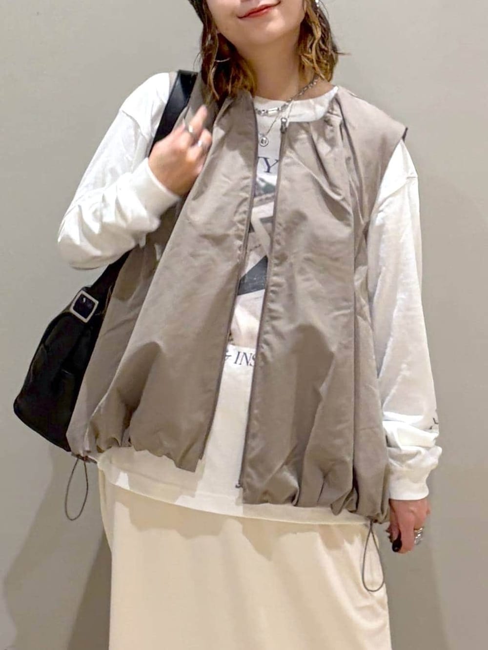 グレー系のベスト、ブラック系のブーツ、ホワイト系のTシャツ/カットソーを着用したレディースの秋コーディネートの2枚目の写真