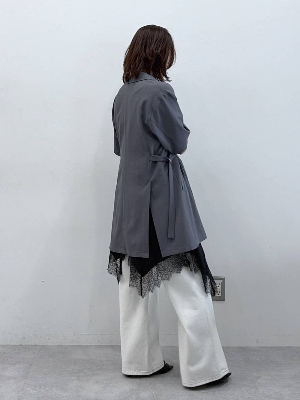 ホワイト系のスラックス、ブラック系のチュニック、ブラック系のサンダルを着用したレディースの春コーディネートの7枚目の写真