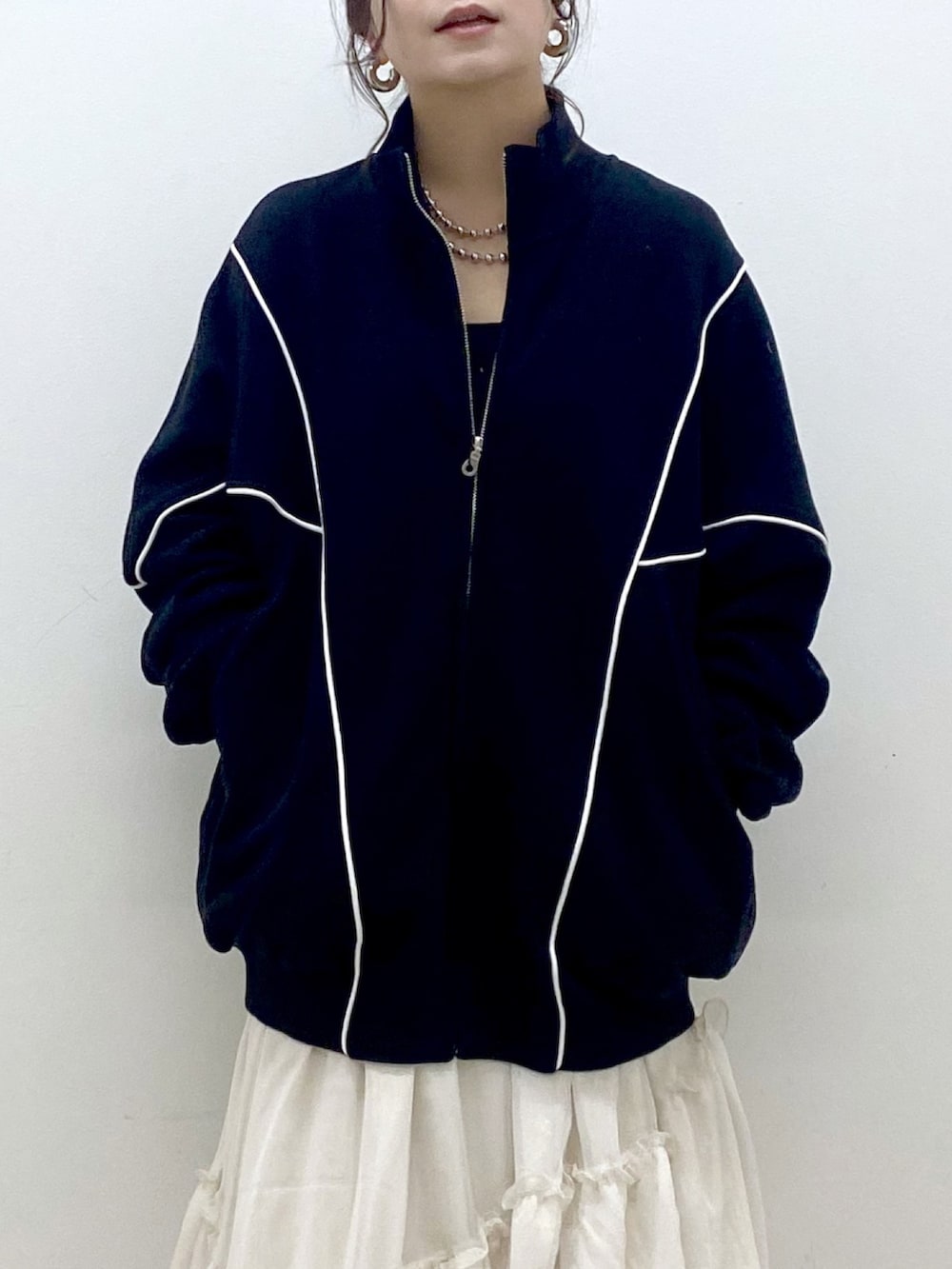 ブラック系のスウェット、ホワイト系のスカート、ホワイト系のローファーを着用したレディースの春コーディネートの2枚目の写真