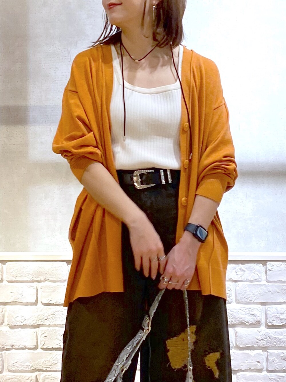 ホワイト系のタンクトップ、オレンジ系のカーディガン/ボレロ、ブラック系のデニムパンツを着用したレディースの春コーディネートの2枚目の写真