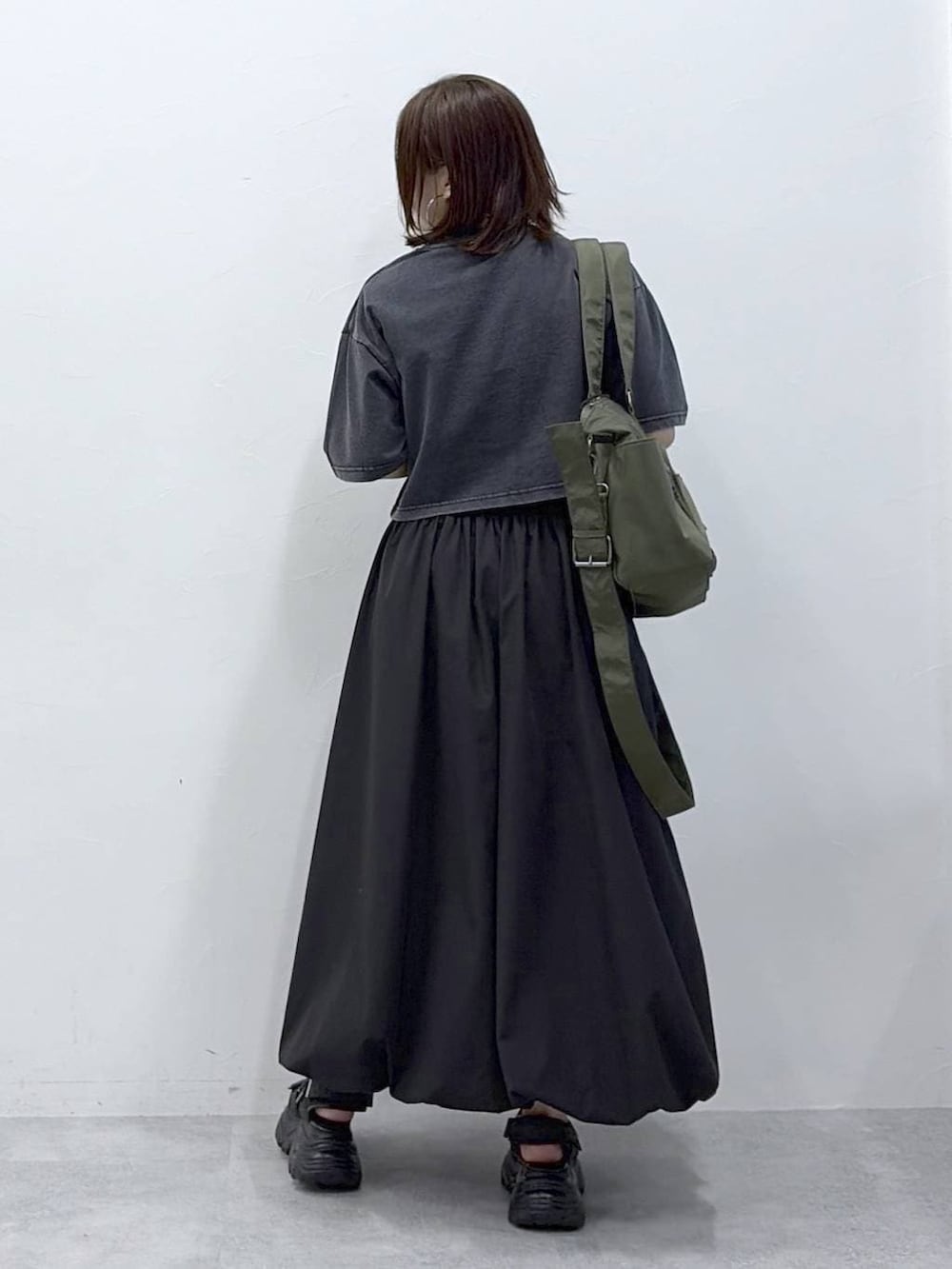 グリーン系のボストンバッグ、ブラック系のサンダル、ブラック系のスカートを着用したレディースの春コーディネートの6枚目の写真