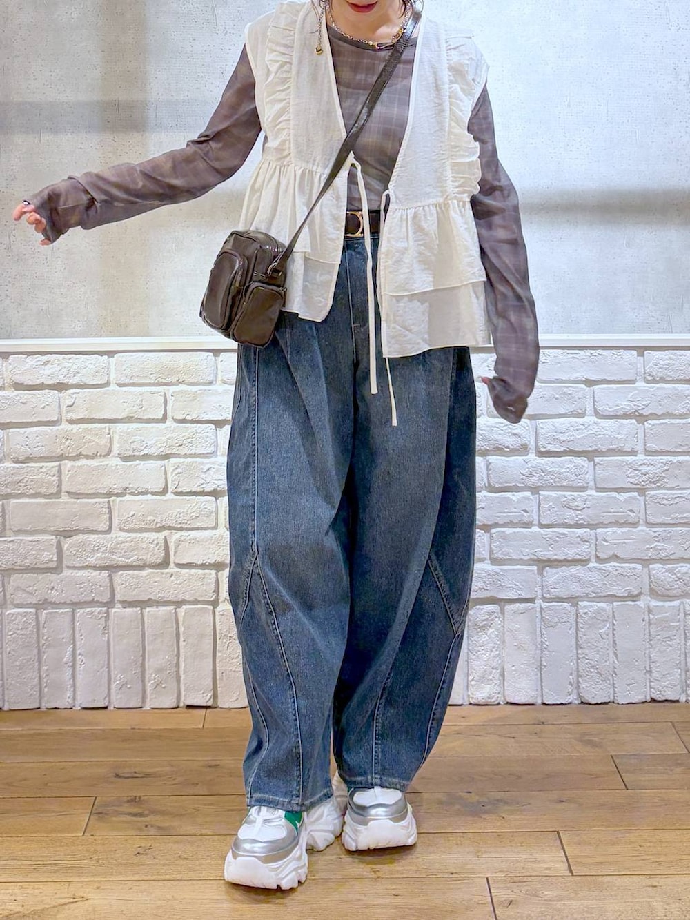 ホワイト系のスニーカー、ブラウン系のショルダーバッグ、ブルー系のデニムパンツを着用したレディースの春コーディネートの3枚目の写真