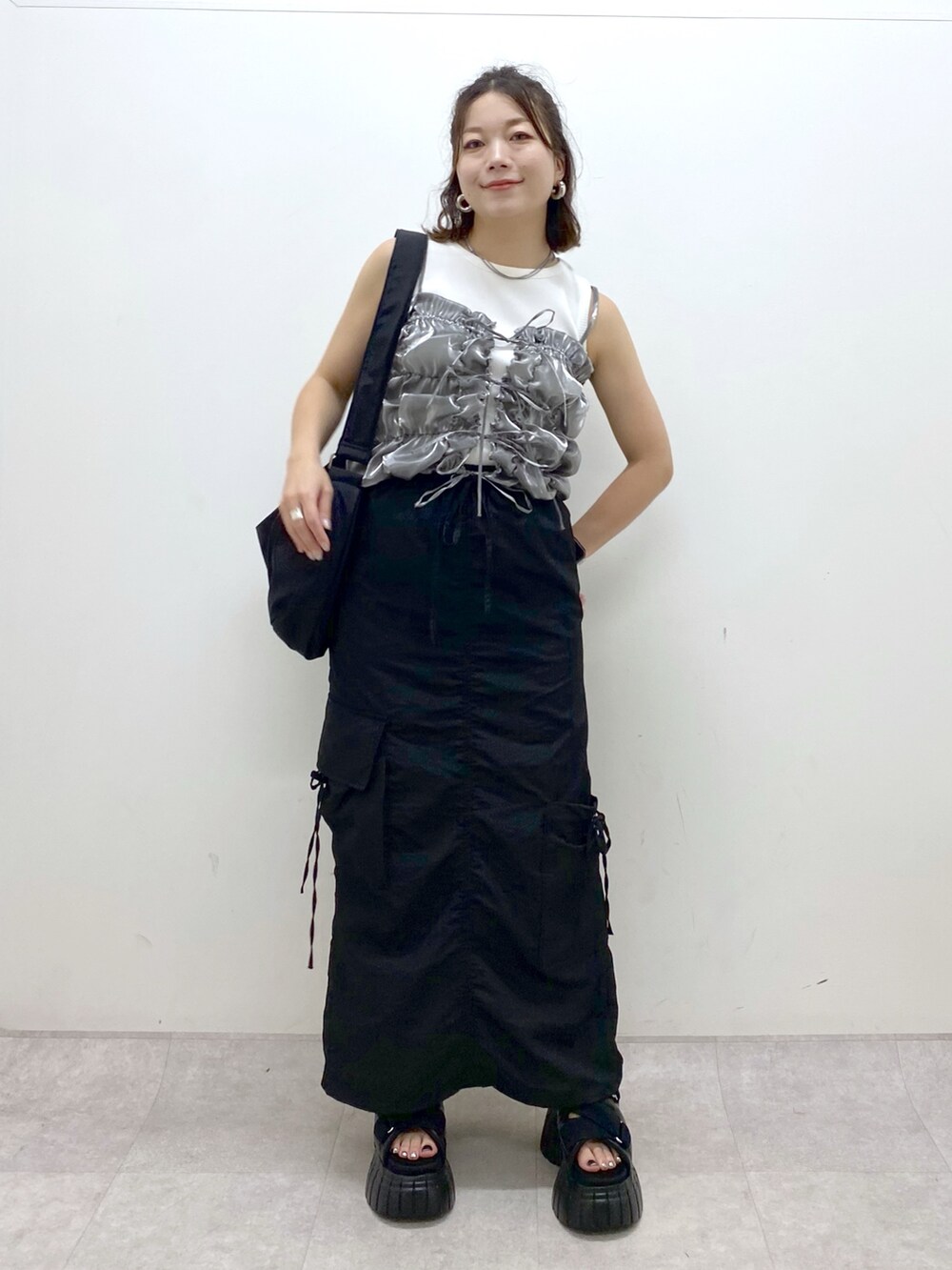 ブラック系のスニーカー、ブラック系のスカート、ブラック系のショルダーバッグを着用したレディースの夏コーディネートの9枚目の写真