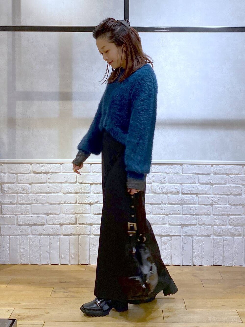 シルバー系のTシャツ/カットソー、ブラック系のブーツ、ブルー系のニット/セーターを着用したレディースの冬コーディネートの6枚目の写真