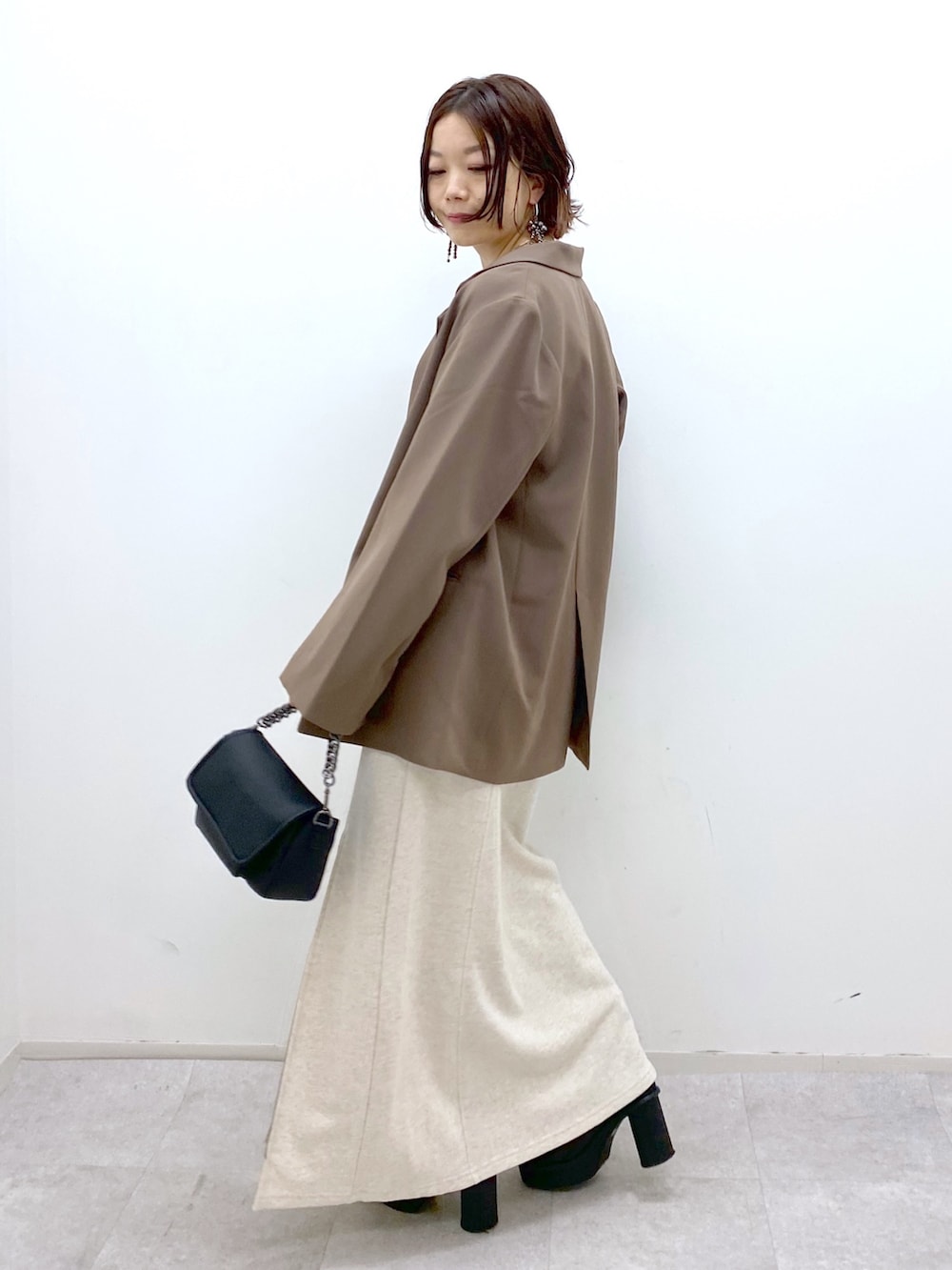 ホワイト系のスカート、ブラック系のブーツ、ブラック系のバッグを着用したレディースの秋コーディネートの3枚目の写真