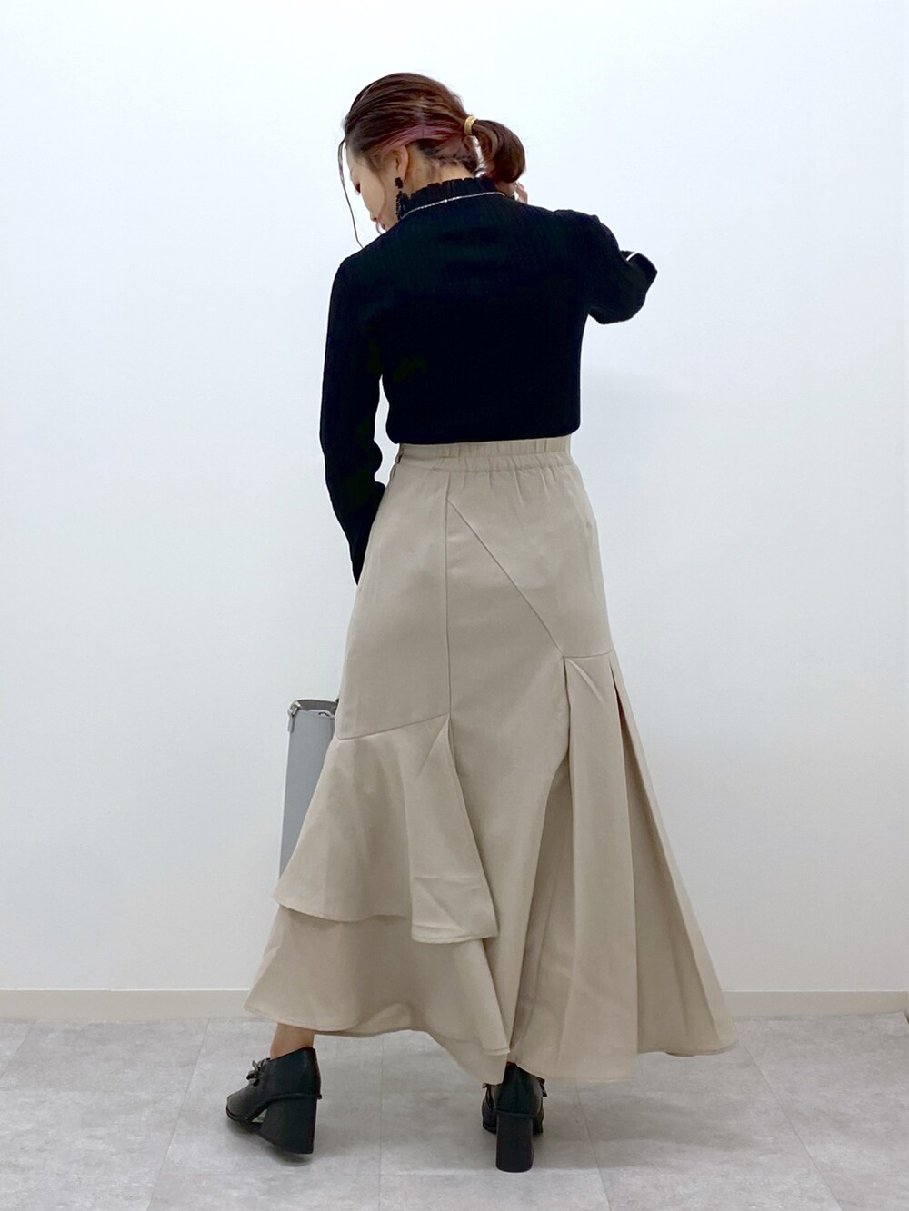 ブラック系のニット/セーター、ベージュ系のスカート、シルバー系のショルダーバッグを着用したレディースの冬コーディネートの3枚目の写真