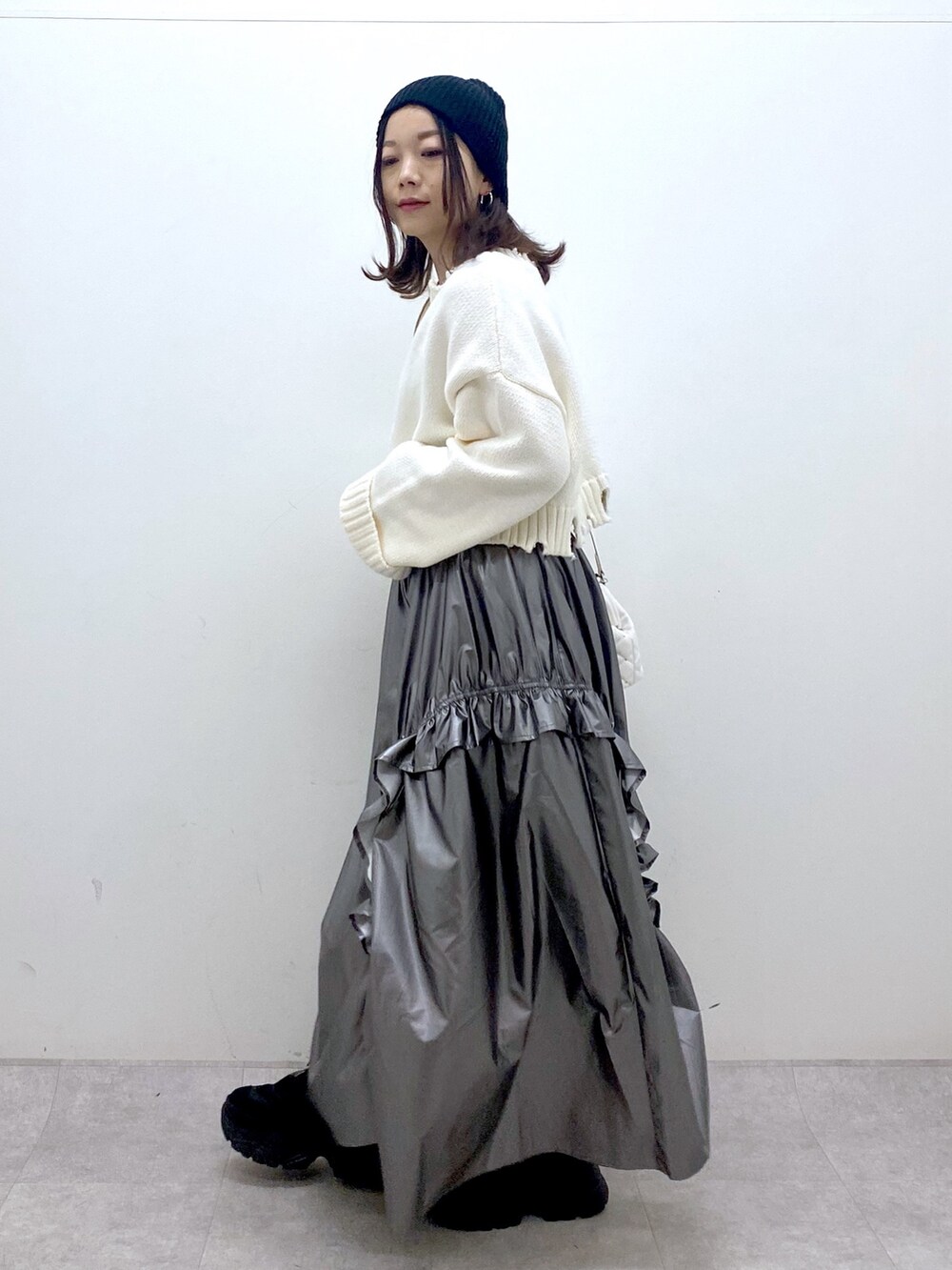 ホワイト系のニット/セーター、シルバー系のスカート、ホワイト系のショルダーバッグを着用したレディースの冬コーディネートの3枚目の写真