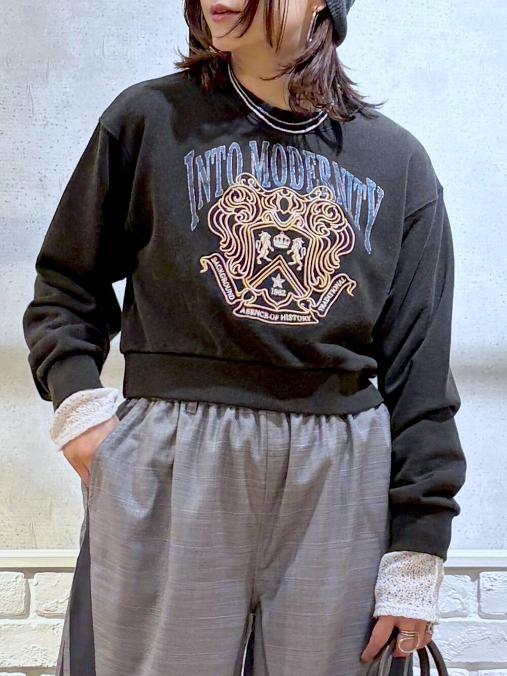 ブラック系のスニーカー、グレー系のスウェット、ブラック系のショルダーバッグを着用したレディースの冬コーディネートの2枚目の写真